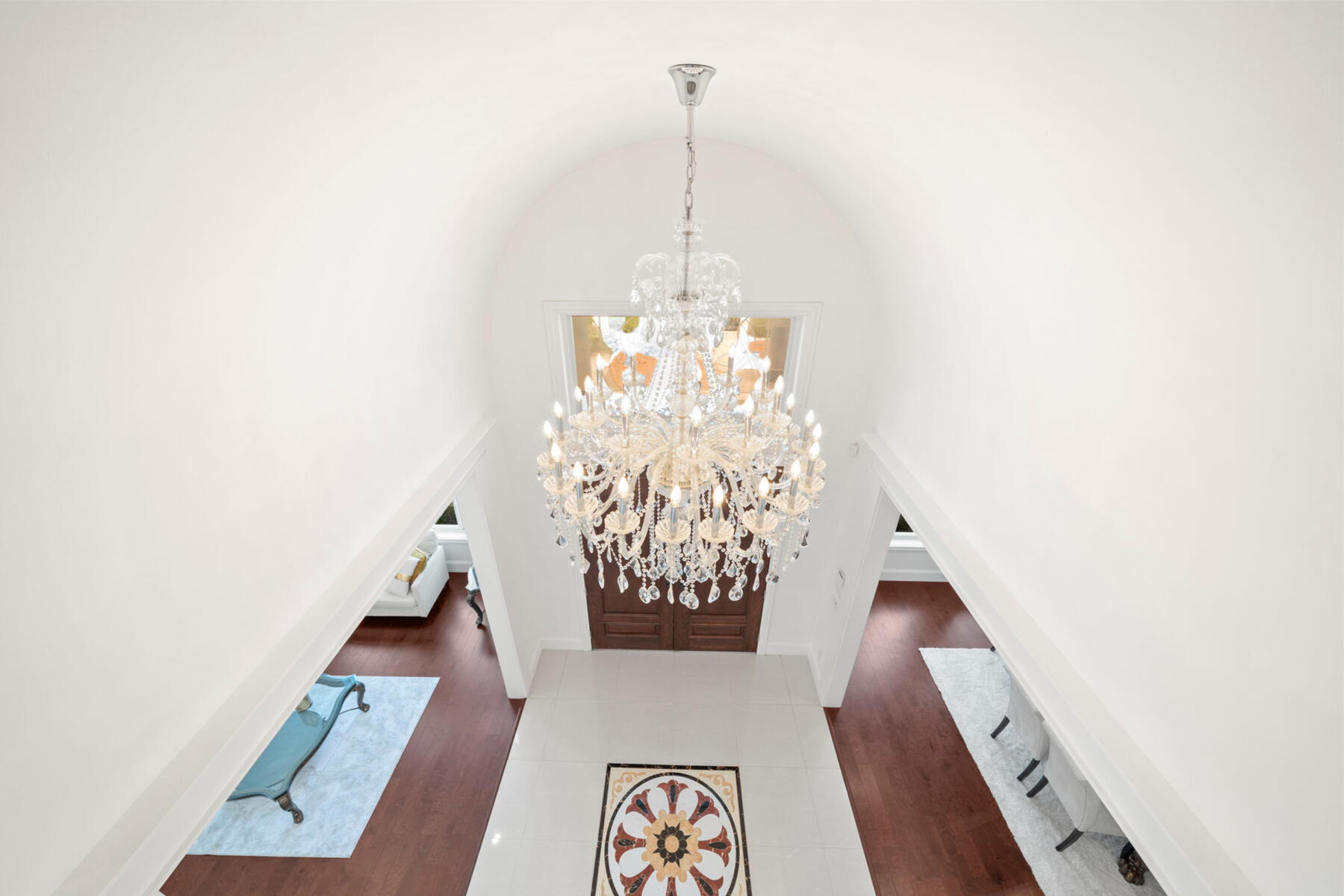 Above, a barrel-vaulted ceiling and statement crystal chandelier reveal the soaring vertical volume at the heart of the home.
